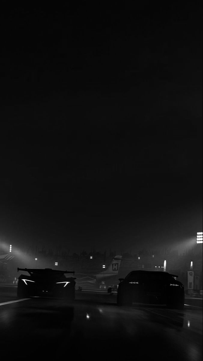 two cars driving down the road in the dark with lights on and fog coming from behind them