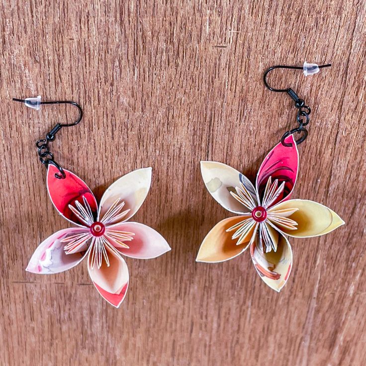 Discover the charm of a truly unique pair of dangle earrings, meticulously handmade and crafted with care. Each set is one of a kind, featuring flowers made from the pages of up-cycled children's books adorned with small colorful beads.  These charming earrings make a delightful accessory for any occasion. Perfect as a unique gift for a loved one, a special touch for back to school, or a stylish addition to your own jewelry collection, these earrings blend timeless elegance with artisanal craftsmanship. Ideal for transforming everyday wear, holiday outfits, or even as a memorable bridesmaid gift, each pair showcases the beauty of handmade artistry.  Celebrate the allure of paper flowers and colorful accents with these distinctive earrings that add a touch of whimsy and sophistication to an Flower Dangle Earrings, Whimsical Style, Keepsake Jewelry, Whimsical Fashion, Style Jewelry, Recycled Paper, Bridesmaid Gift, Children's Books, Holiday Outfits