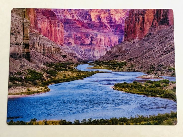 a river in the middle of a canyon surrounded by mountains and trees on either side