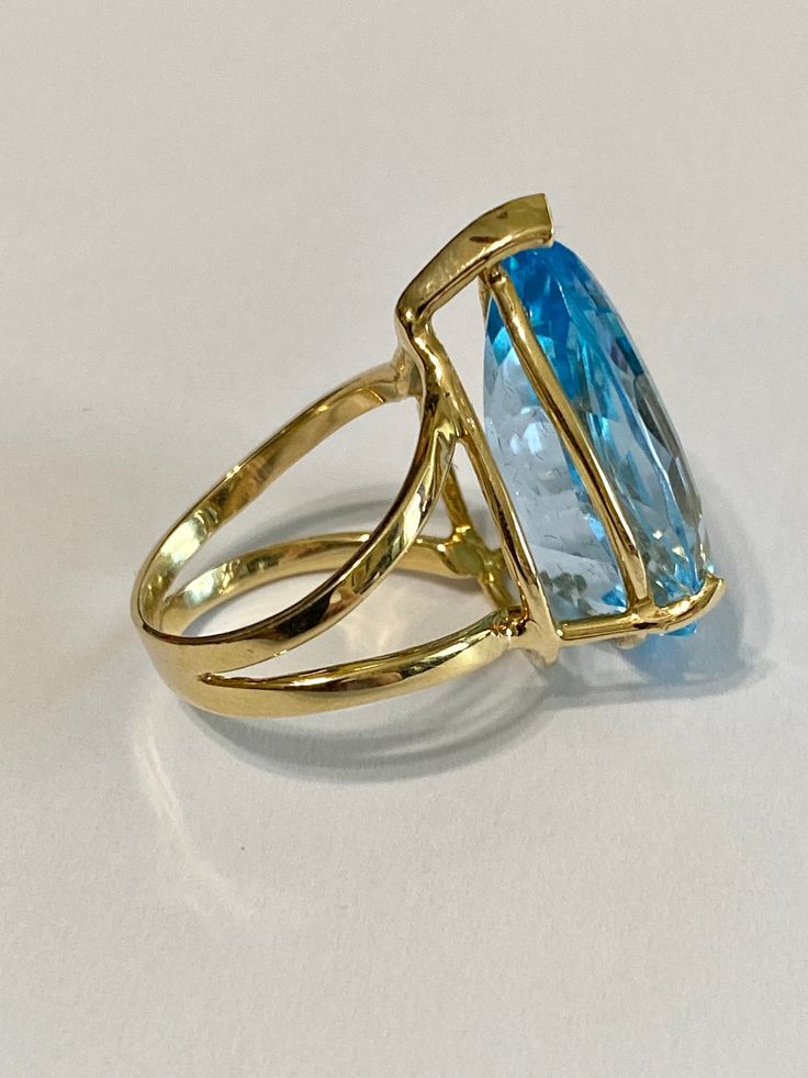 Stunning statement 14k yellow gold genuine blue topaz ring! This gorgeous ring contains a faceted pear cut genuine blue Topaz gemstone that weighs approximately 27.32 carats! The pear shaped gem is secured by 3 thick prongs. Incredible piece of fine jewelry featuring December birthstone! ERA - Modern, Estate METAL / MATERIAL - 14k yellow gold, 1 genuine Blue Topaz (approx. 27.32 cts) MARKINGS / HISTORY - Inside of ring is marked 14k CONDITION - Great vintage condition. SIZE / MEASUREMENTS - Size Fine Jewelry Yellow Gold Topaz Ring With Teardrop, Fine Jewelry Yellow Gold Topaz Teardrop Ring, Blue Topaz Teardrop Ring Fine Jewelry, Formal Yellow Gold Topaz Teardrop Ring, Formal Blue Pear-shaped Topaz Ring, Fine Jewelry Blue Pear-shaped Topaz Ring, Gold Teardrop Topaz Ring For Formal Occasions, Fine Blue Topaz Ring Pear-shaped, Formal Teardrop Blue Topaz Ring