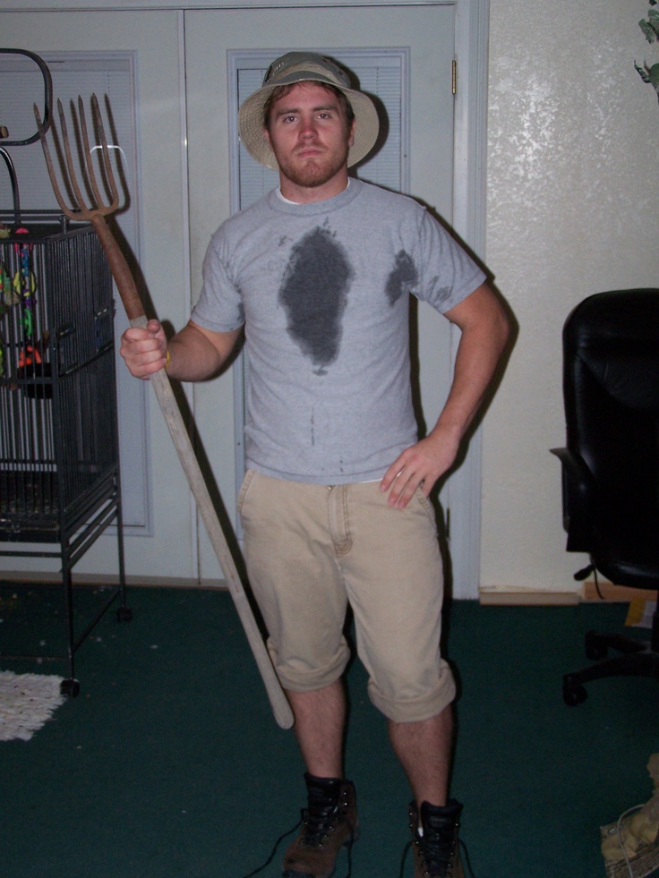 a man holding a large metal pitchfork in his hand and wearing a hat on top of it