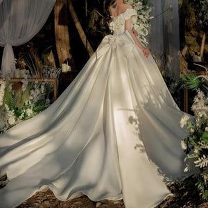 a woman in a white wedding dress standing next to an arch with flowers on it