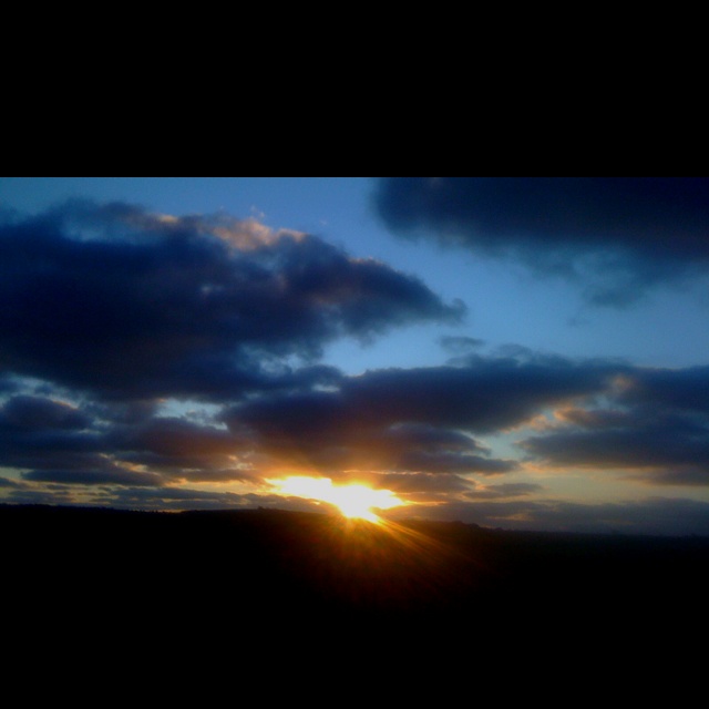 the sun is setting behind some clouds in the sky