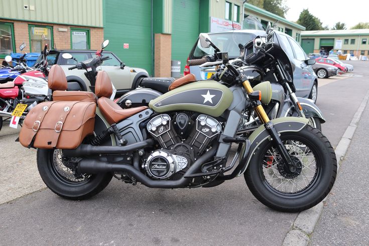 two motorcycles parked next to each other in front of a building with cars behind them