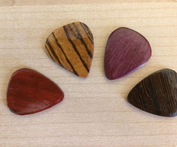 four wooden guitar picks sitting on top of a table