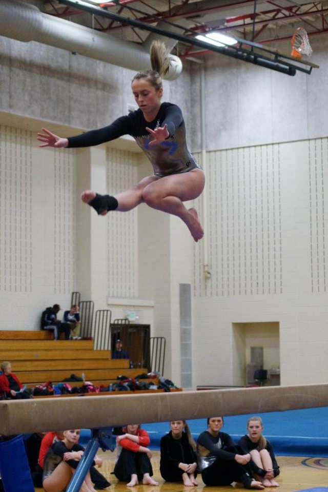 a woman jumping in the air on top of a trampoline while people watch