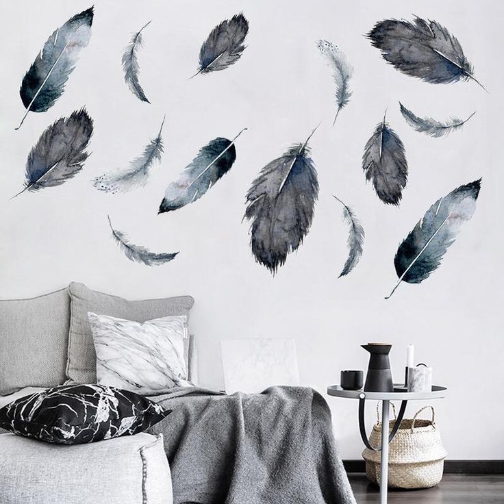 a bed room with a white wall and some black feathers on the wall next to it