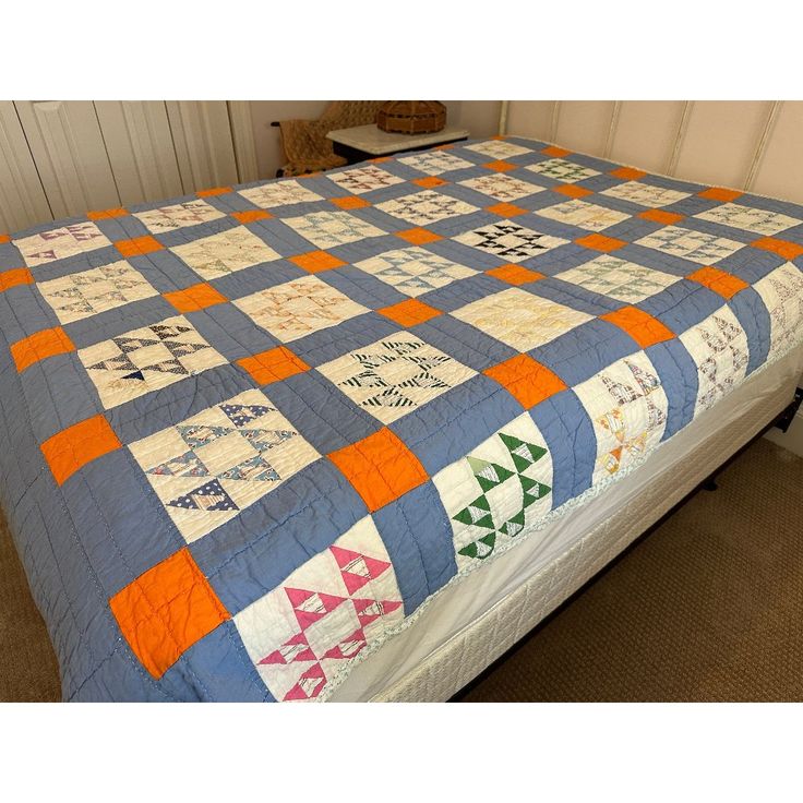 a bed with a blue and orange quilt on it