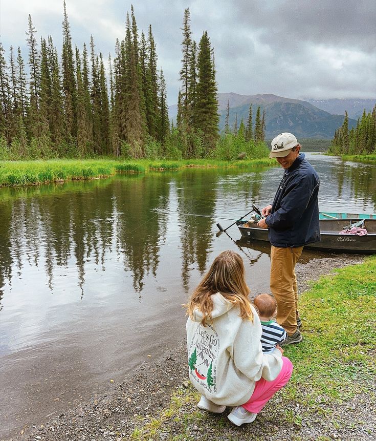 a father and daughter fishing on the shore of a lake