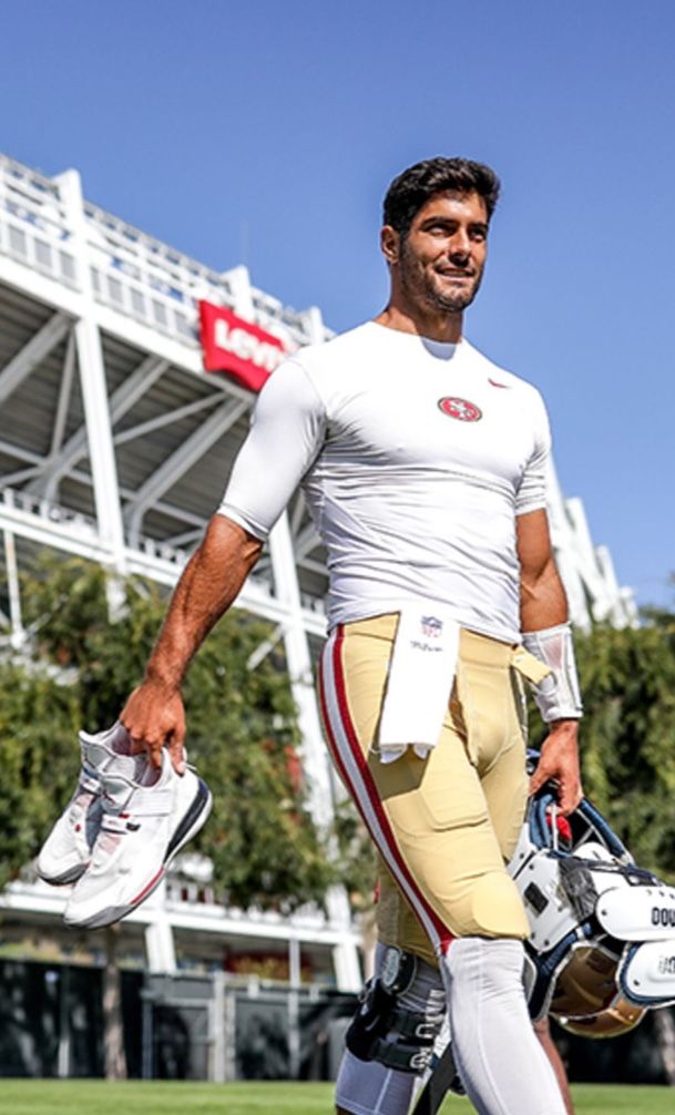 a football player is walking on the field with his helmet and gloves in hand,