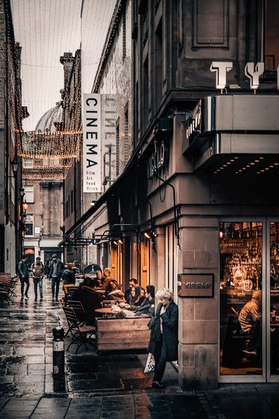 people are walking down the street in front of an old movie theater on a rainy day