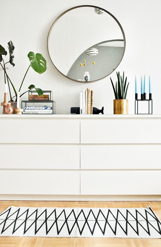 a white dresser topped with a mirror and plants