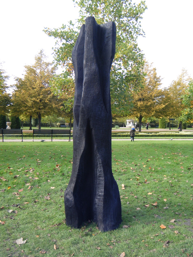 a large black piece of art sitting in the middle of a field