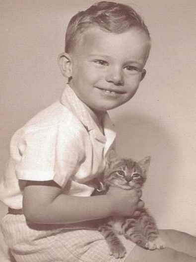 a young boy holding a kitten in his arms