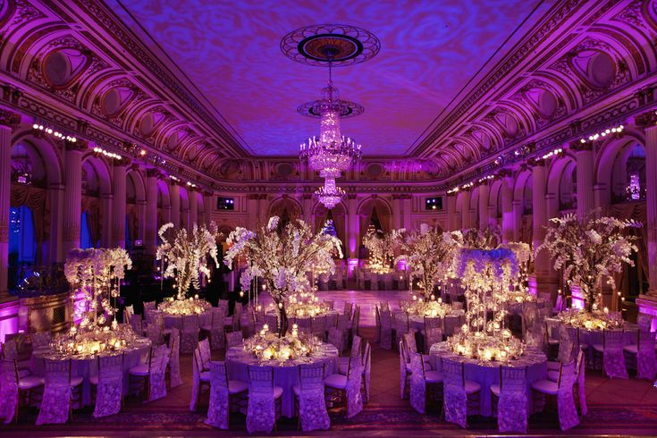 a banquet hall with tables and chairs covered in purple lighting