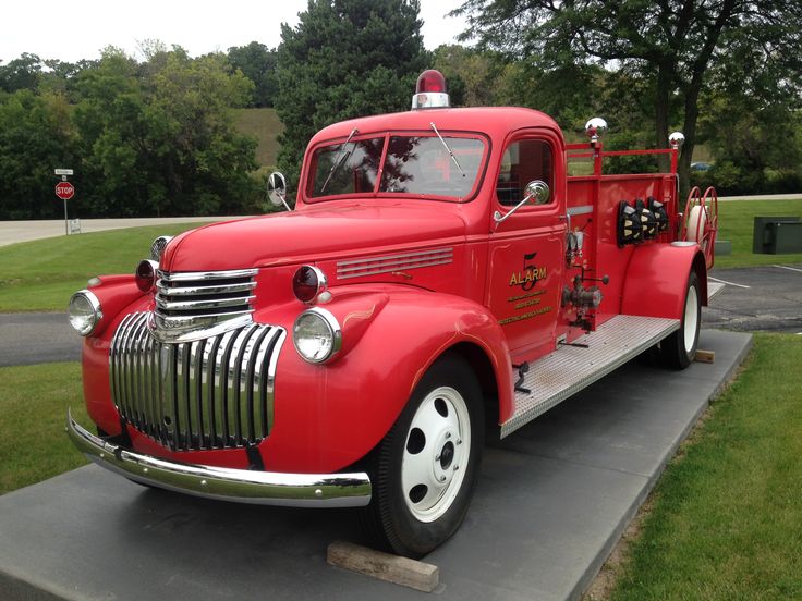 an old red fire truck is parked on the sidewalk