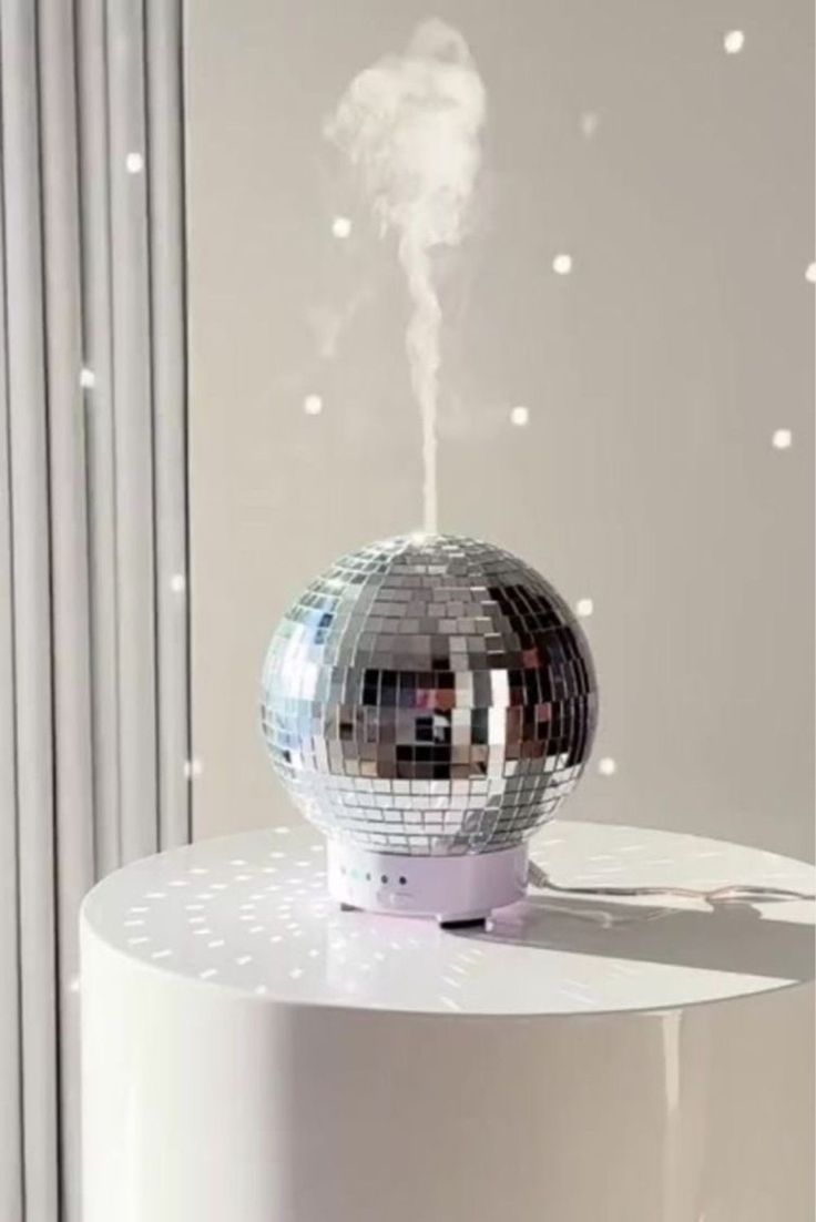 a silver disco ball sitting on top of a white table next to a mirror wall