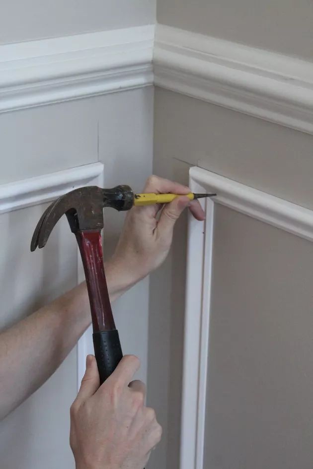 a man is holding a hammer and pointing it at the wall with his right hand