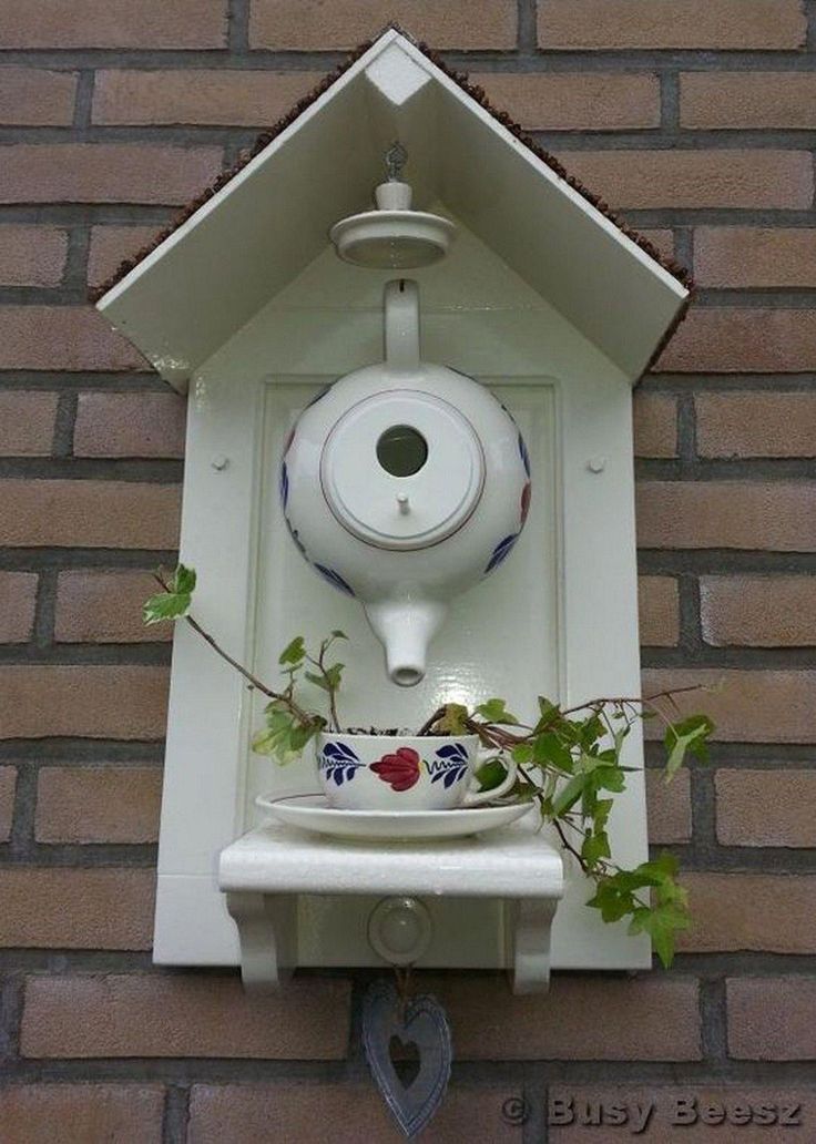 a bird house with a bowl on the top and a plant growing out of it