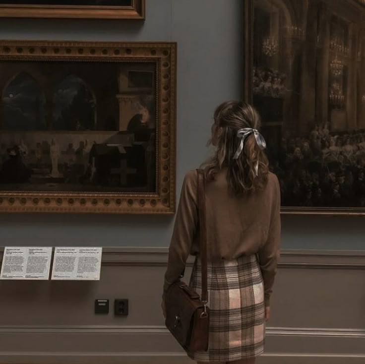 a woman standing in front of a painting and looking at the paintings on the wall