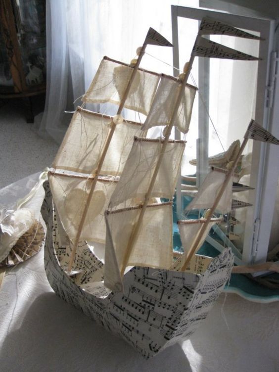 a boat made out of sheet music is sitting on the floor in front of a window