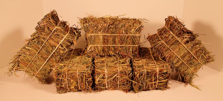 several bundles of hay stacked on top of each other in front of a white wall