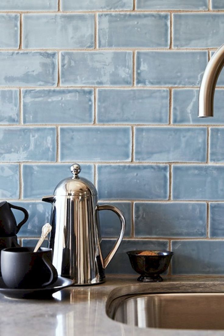 a kitchen sink with a kettle and cups on it