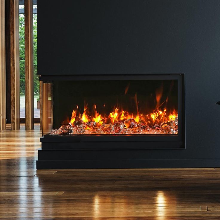 a modern fireplace with bright flames and wood flooring in a living room, along with dark walls