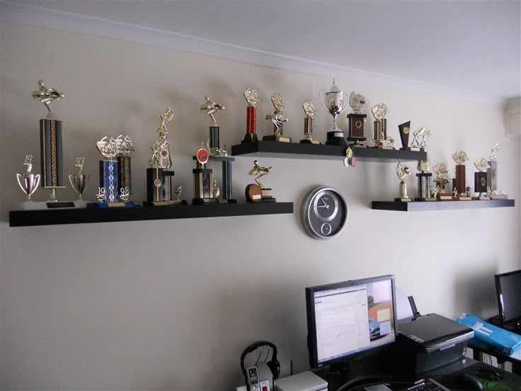 there are many trophies on the shelves above the computer