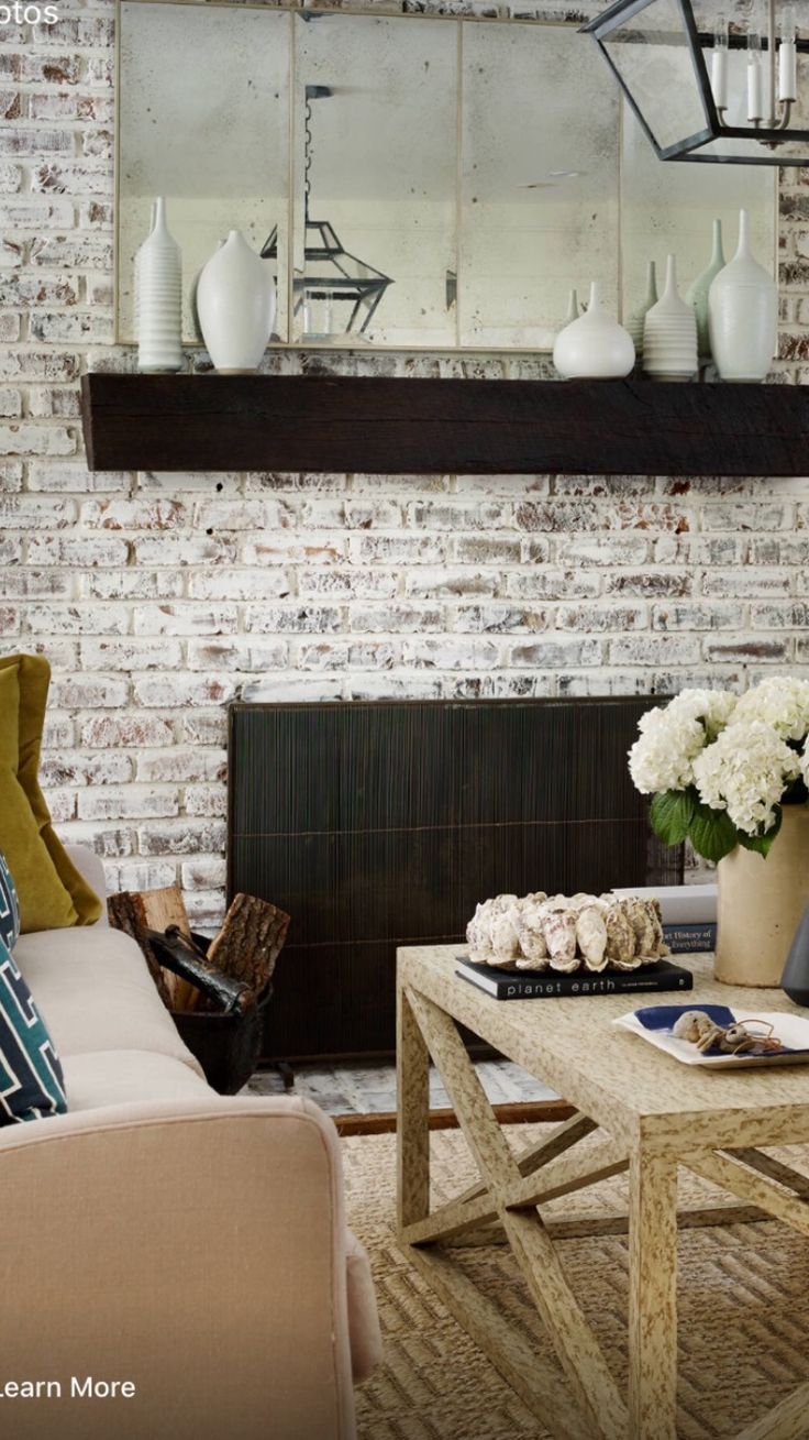 a living room filled with furniture and a fire place in front of a brick wall