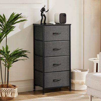 a tall black cabinet with five drawers next to a potted plant in a living room