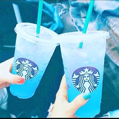 two people holding up starbucks cups with green straws