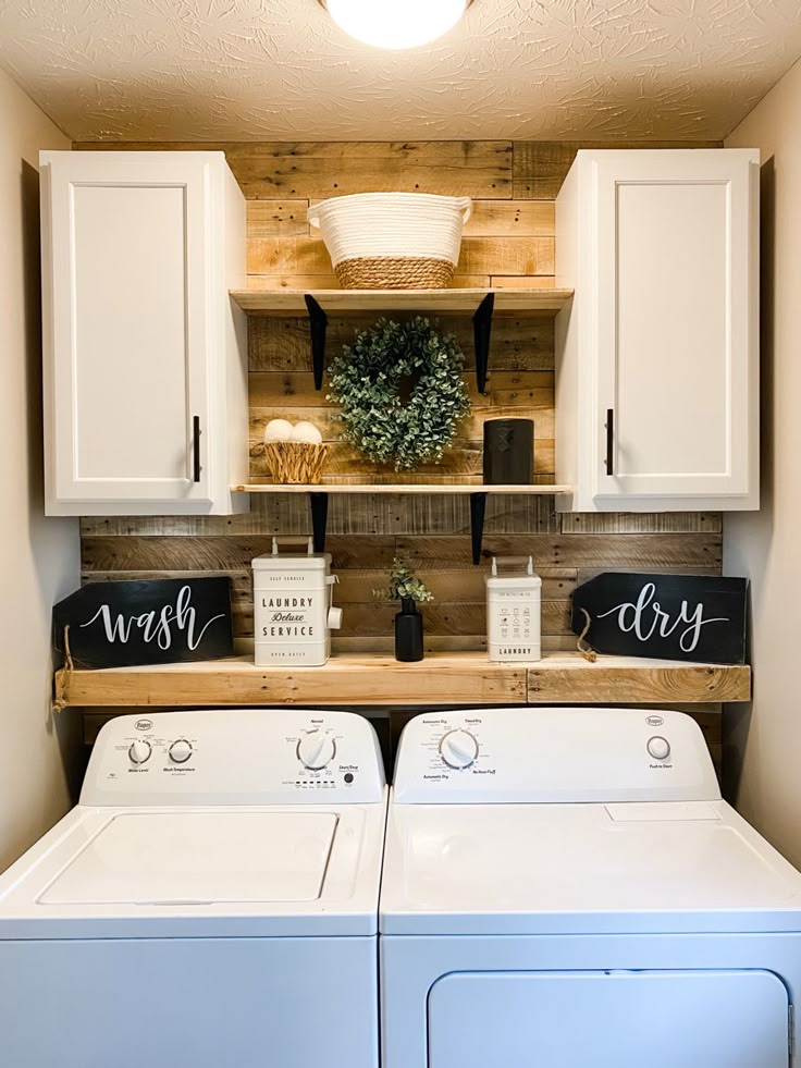 a washer and dryer in a room with wooden shelves on the wall above them