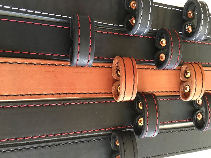 three black and brown leather pieces with red stitching on each side, hanging from the wall