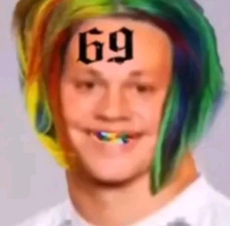 a young man with rainbow hair has the number 69 painted on his forehead and is smiling