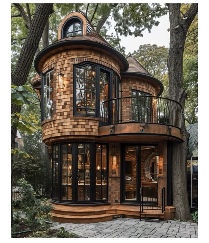 a round house with lots of windows and balconies on the top floor, surrounded by trees