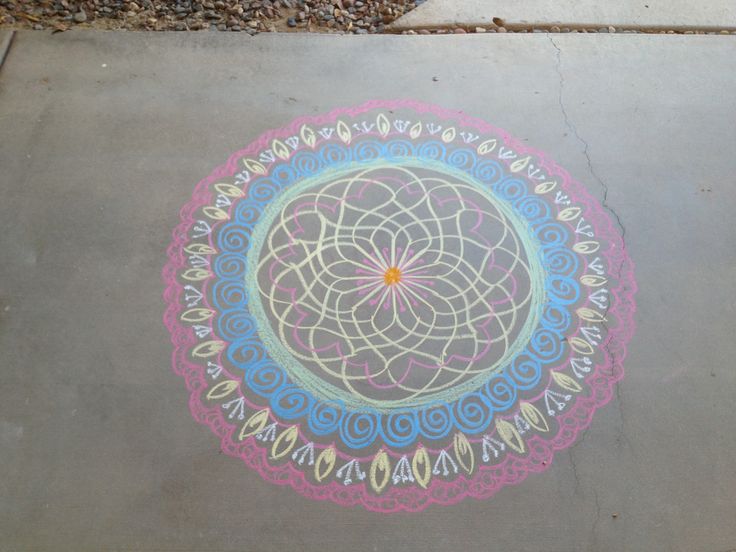 a colorful drawing on the ground in front of a sidewalk with gravel and rocks around it