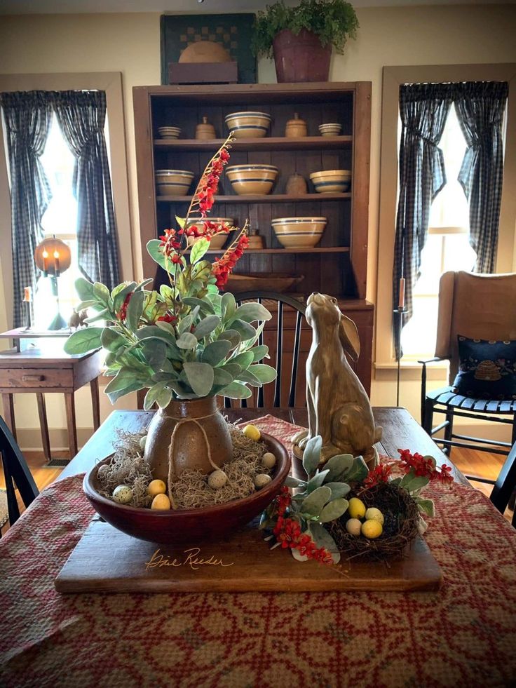 a wooden table topped with a bowl filled with plants and rocks next to a potted plant