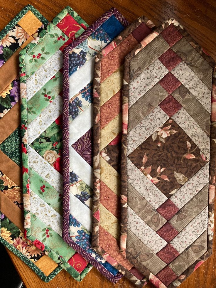 several different types of quilts laid out on a wooden table with a cell phone next to them