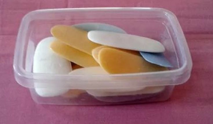 several spoons in a plastic container on a pink cloth covered tablecloth with white and yellow food