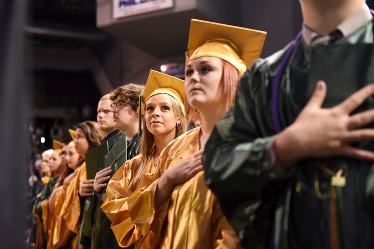 people in graduation gowns and caps stand together at the end of a line with their hands folded