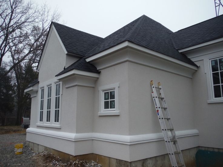 a house being painted white with a ladder leaning against it