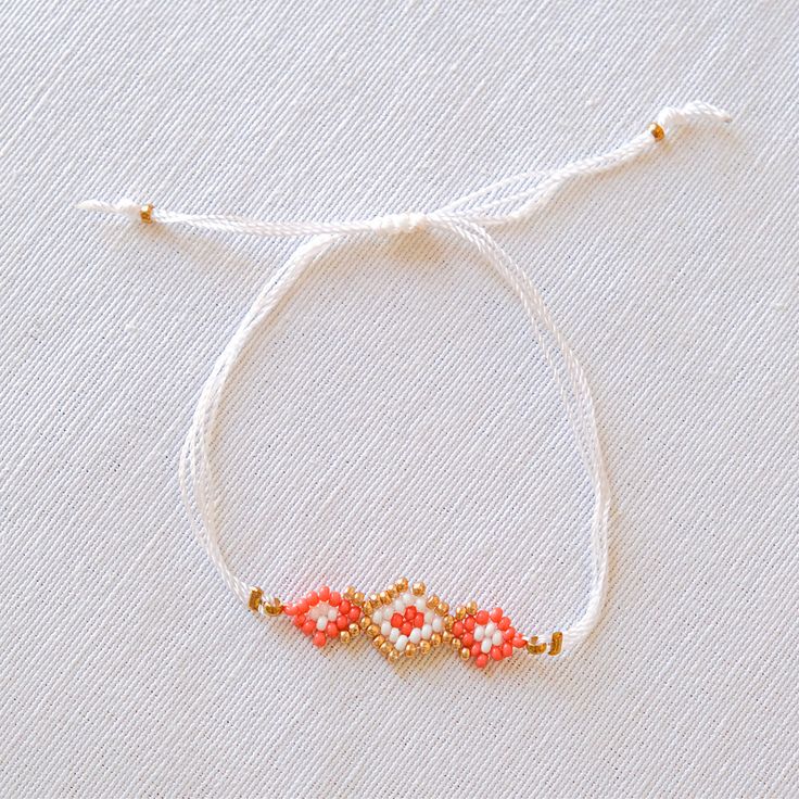 the beaded bracelet is made with red beads and gold accents on a white background