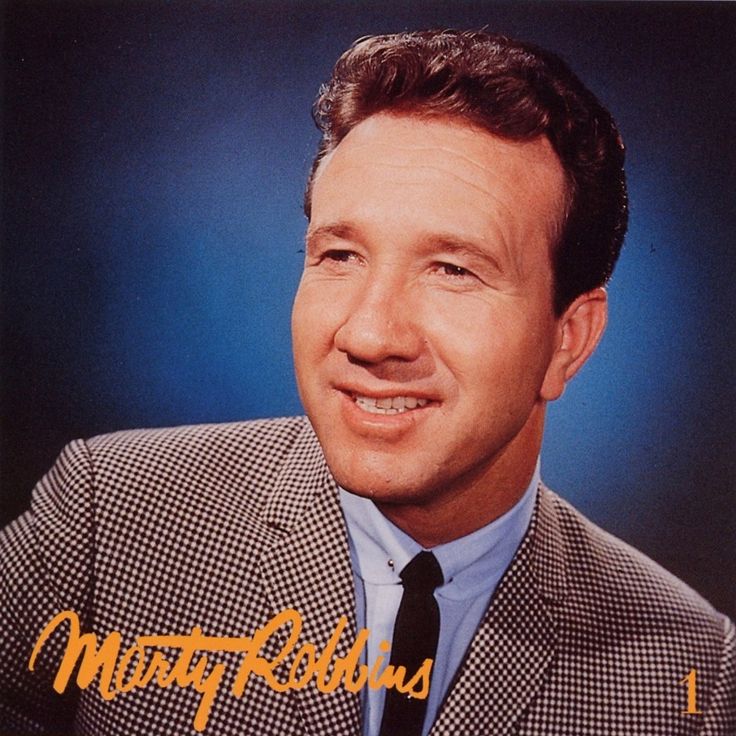 a man in a suit and tie smiling for the camera with an autographed photo behind him