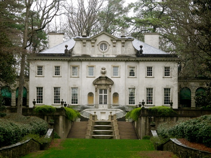 a large white house surrounded by trees with lots of leaves on the ground and stairs leading up to it