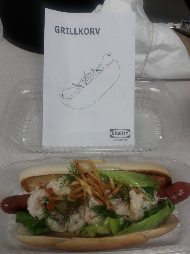 a hot dog with toppings in a plastic container next to a sign that says grillikov