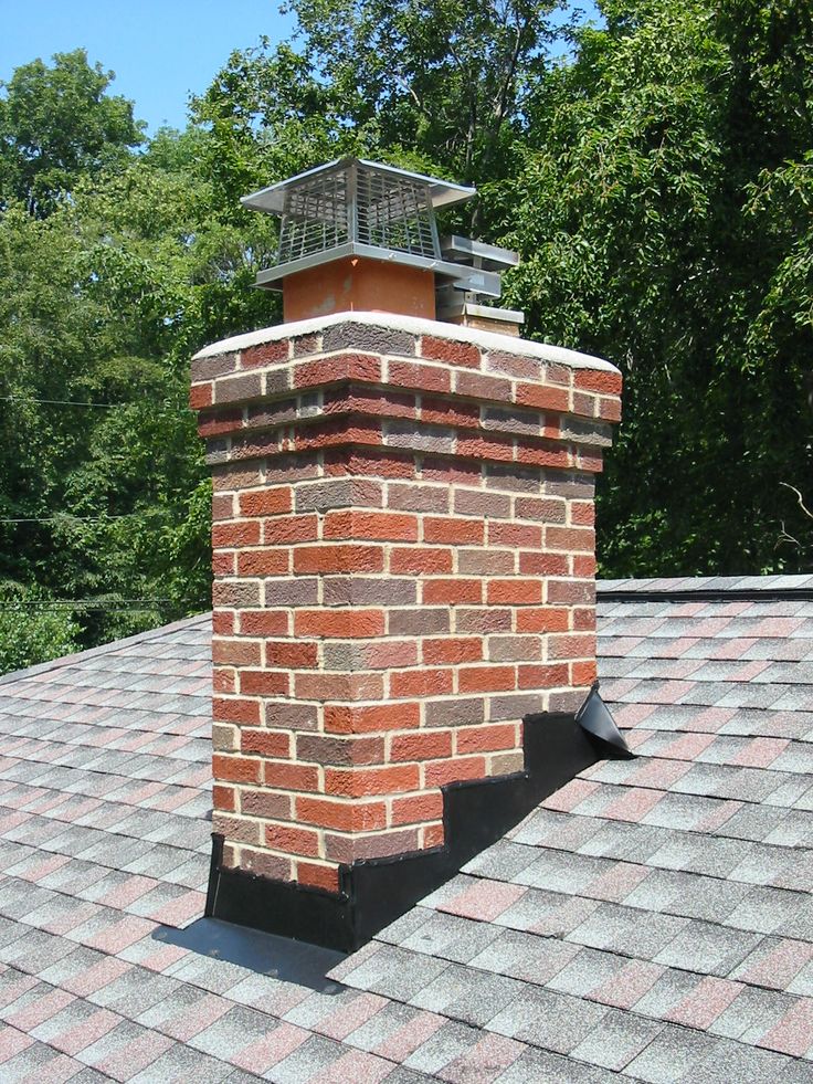 a brick chimney on top of a roof with trees in the backgrouds