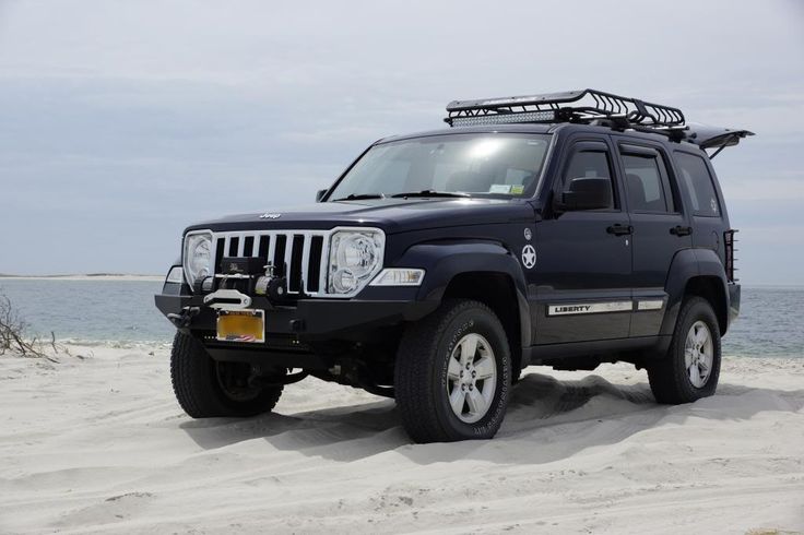 the jeep is parked on the beach by the water's edge with its roof rack up