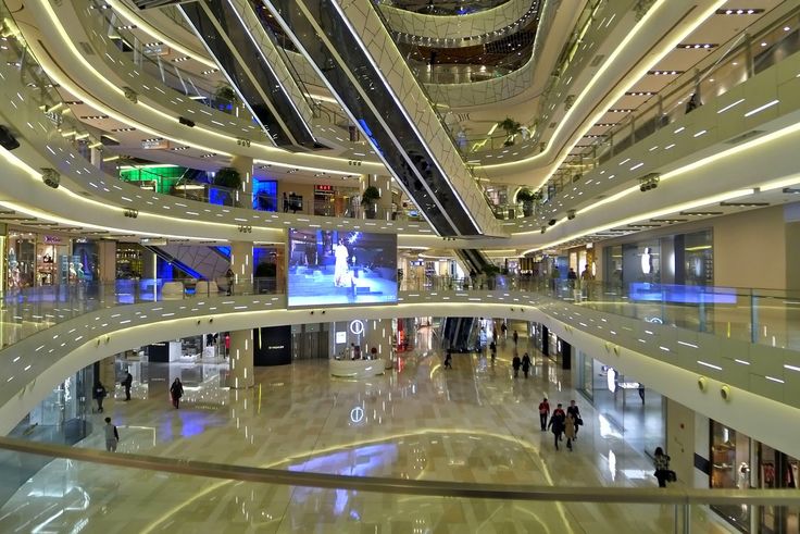 the inside of a shopping mall with people walking around and lots of lights on them