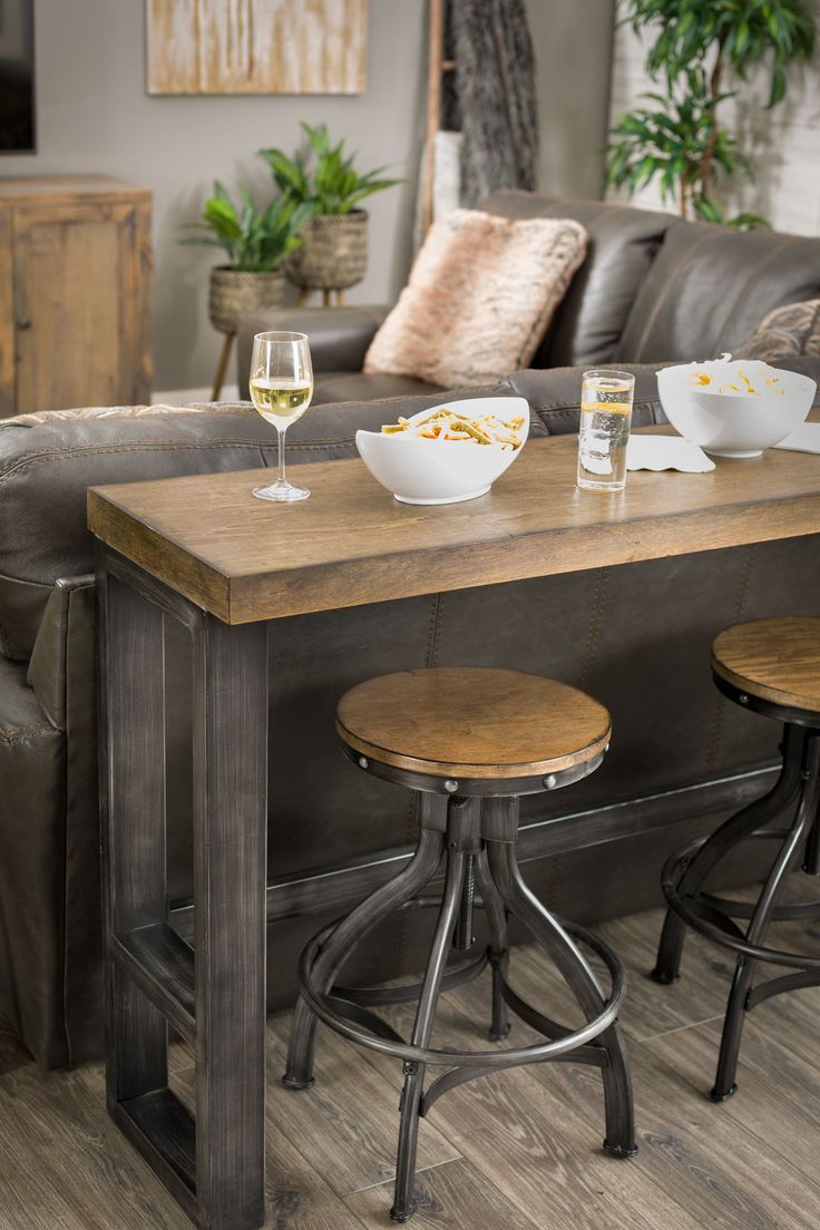 two chairs and a table with food on it in front of a couch at the foot of a sofa